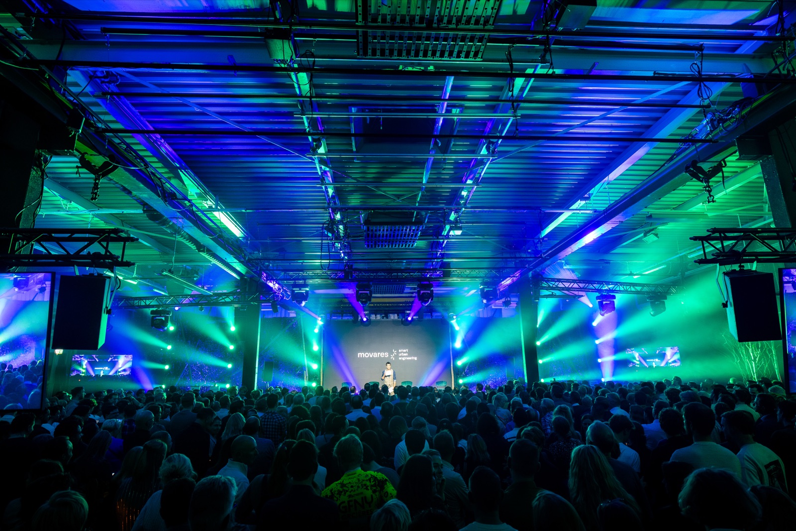 Groot bedrijfsevenement met een volle zaal en sfeervolle podiumverlichting